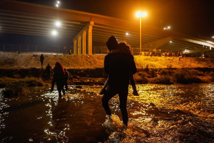 Migrants cross the Rio Grande river and US-Mexico border into El Paso, Texas as seen from...