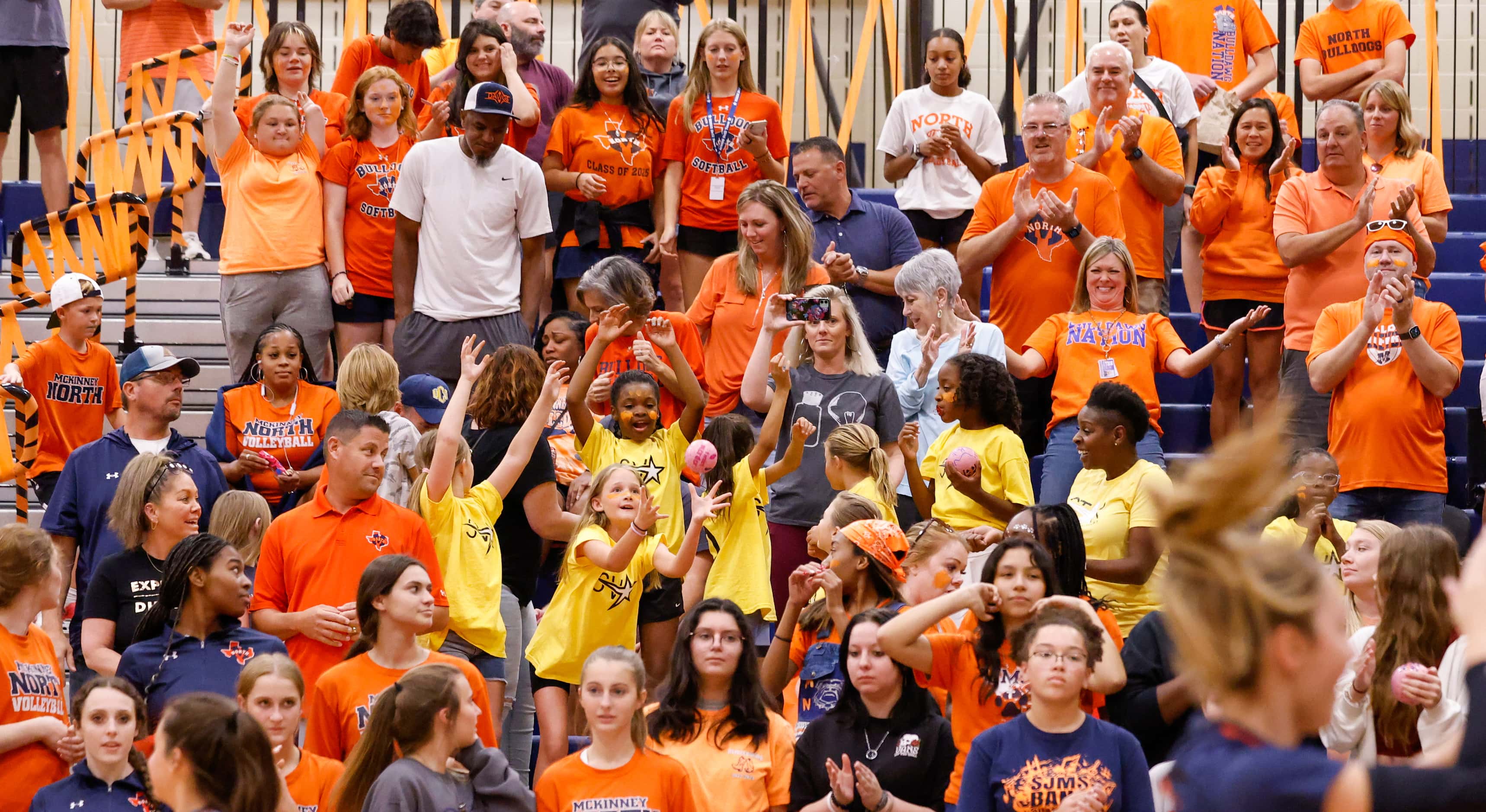 McKinney North fans reach to catch a mini volleyball thrown by players before the start of a...