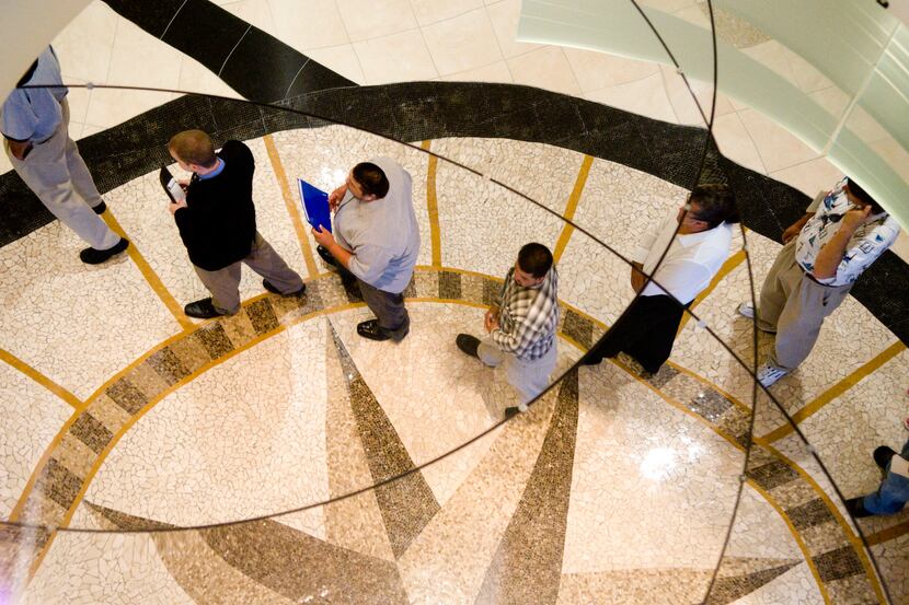 Job seekers are reflected in a mirror on the ceiling as they line up to register for an...