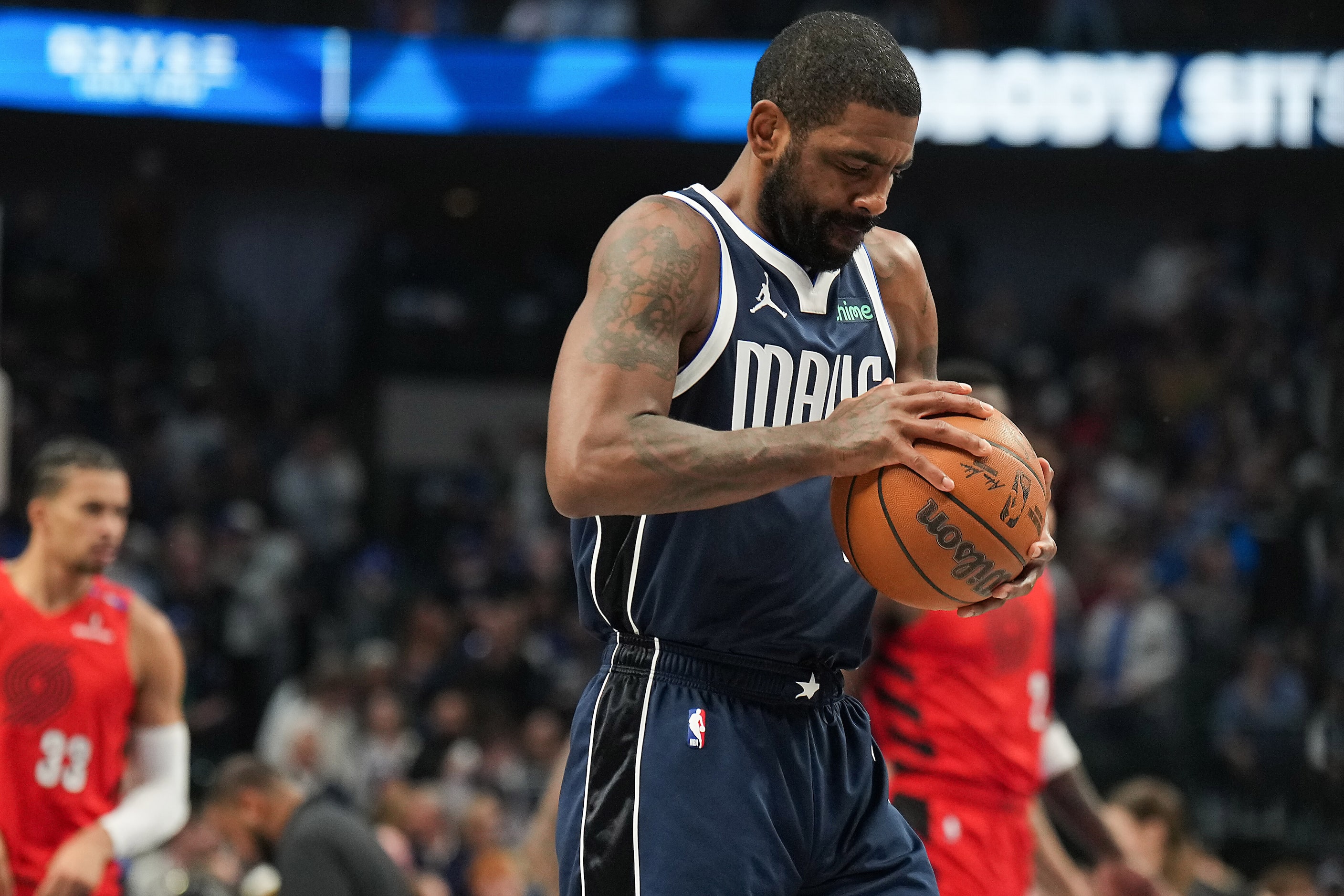 Dallas Mavericks guard Kyrie Irving squeezes the game ball before the opening tipoff of an...