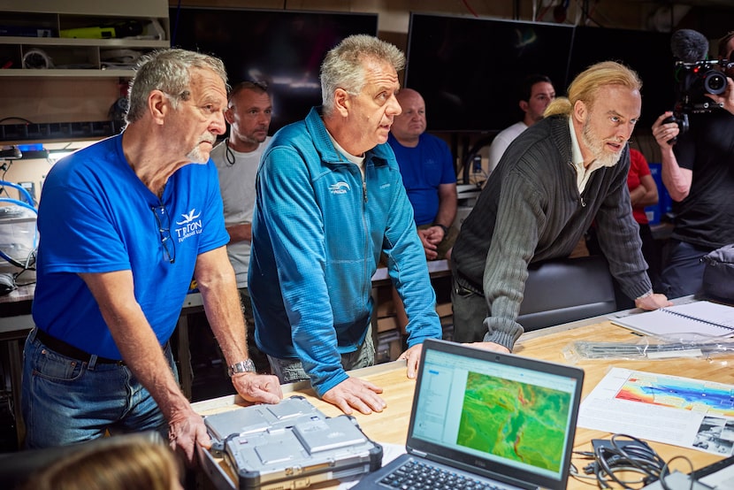 Victor Vescovo (Right) listens to crew members as they discuss one of his ocean dives.