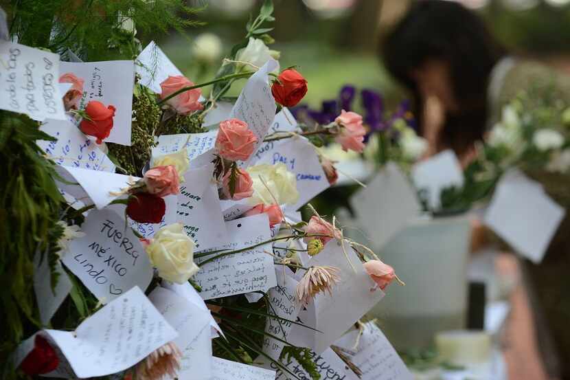 People start a memorial with flowers at a park in front of one of the collapsed buildings in...