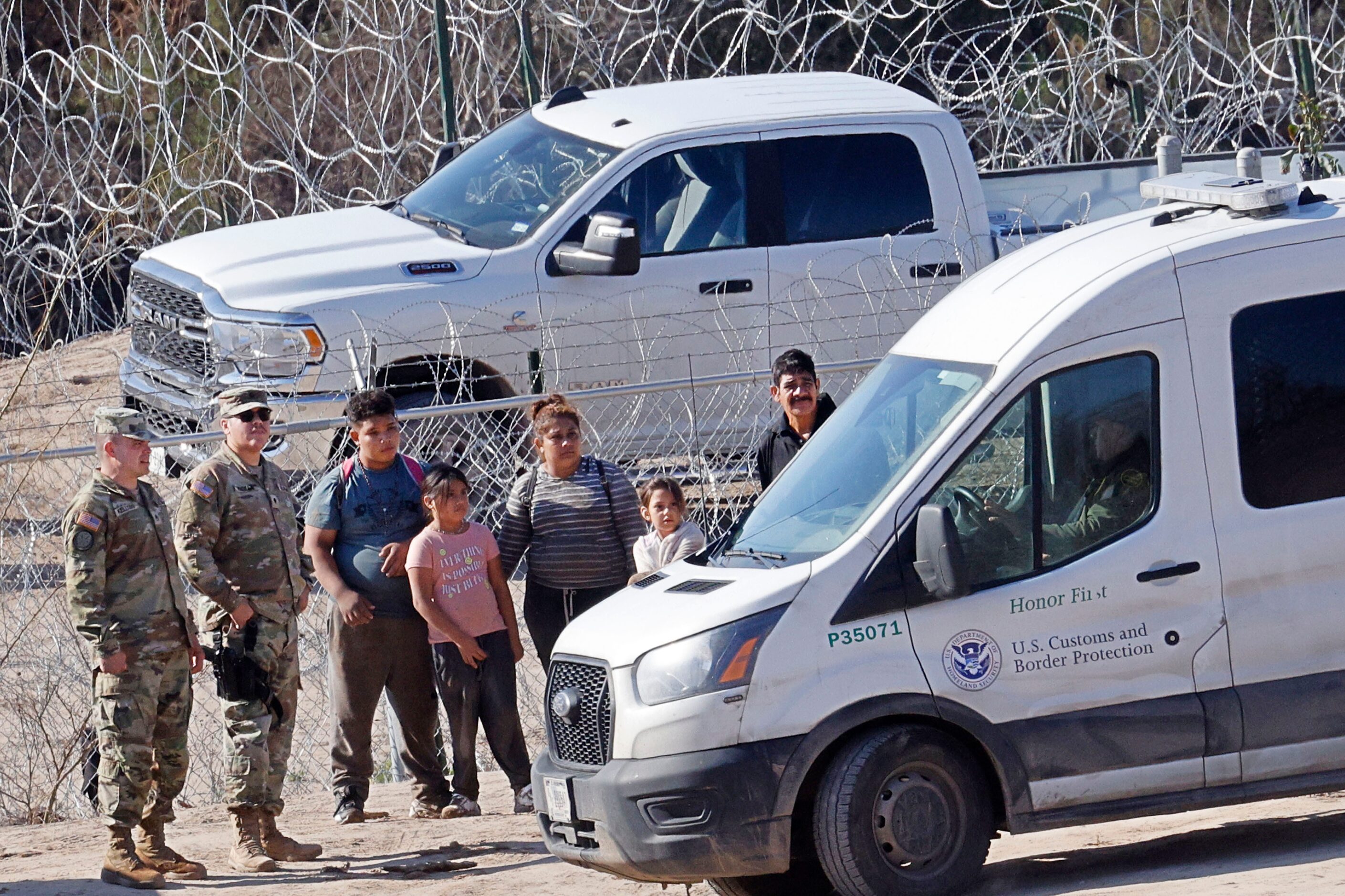 Migrants are escorted by U.S. soldiers with the 508th Military Police Company from New...