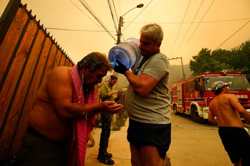 ARCHIVO - Un hombre ayuda a un vecino a refrescarse con una botella de agua mientras los...