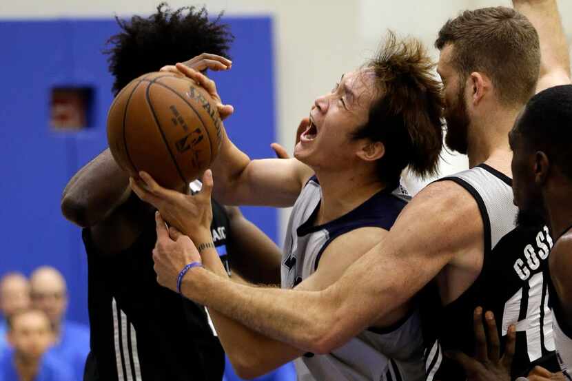 Dallas Mavericks' Ding Yanyuhang, center, struggles to shoot as he is trapped between...