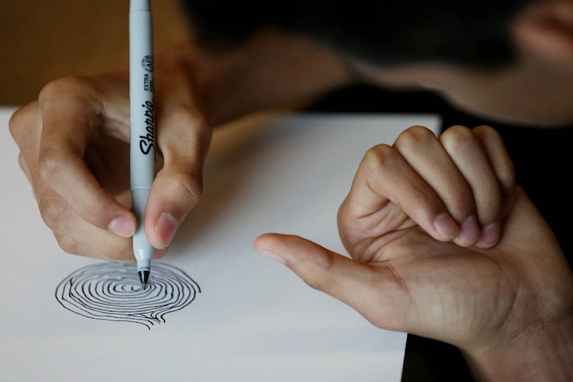 A student draws his thumb during a class lead by teacher Kyle Clark.