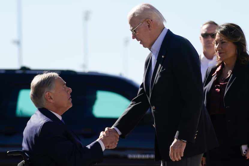President Joe Biden shakes hands with Texas Gov. Greg Abbott as he arrives at El Paso...