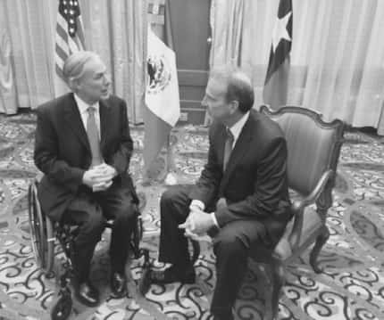 Gov. Greg Abbott confers with former U.S. Ambassador Tony Garza, a former Texas railroad...