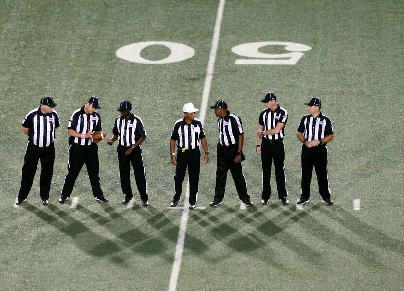 Seven referees prepare to officate the Irving-DeSoto high school football game in Irving,...