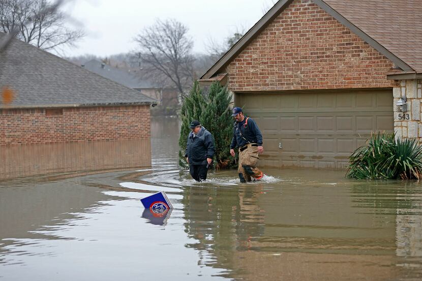 Rodger Williams (left) leaves his flooded house on Lakeside Drive with a firefighter in...