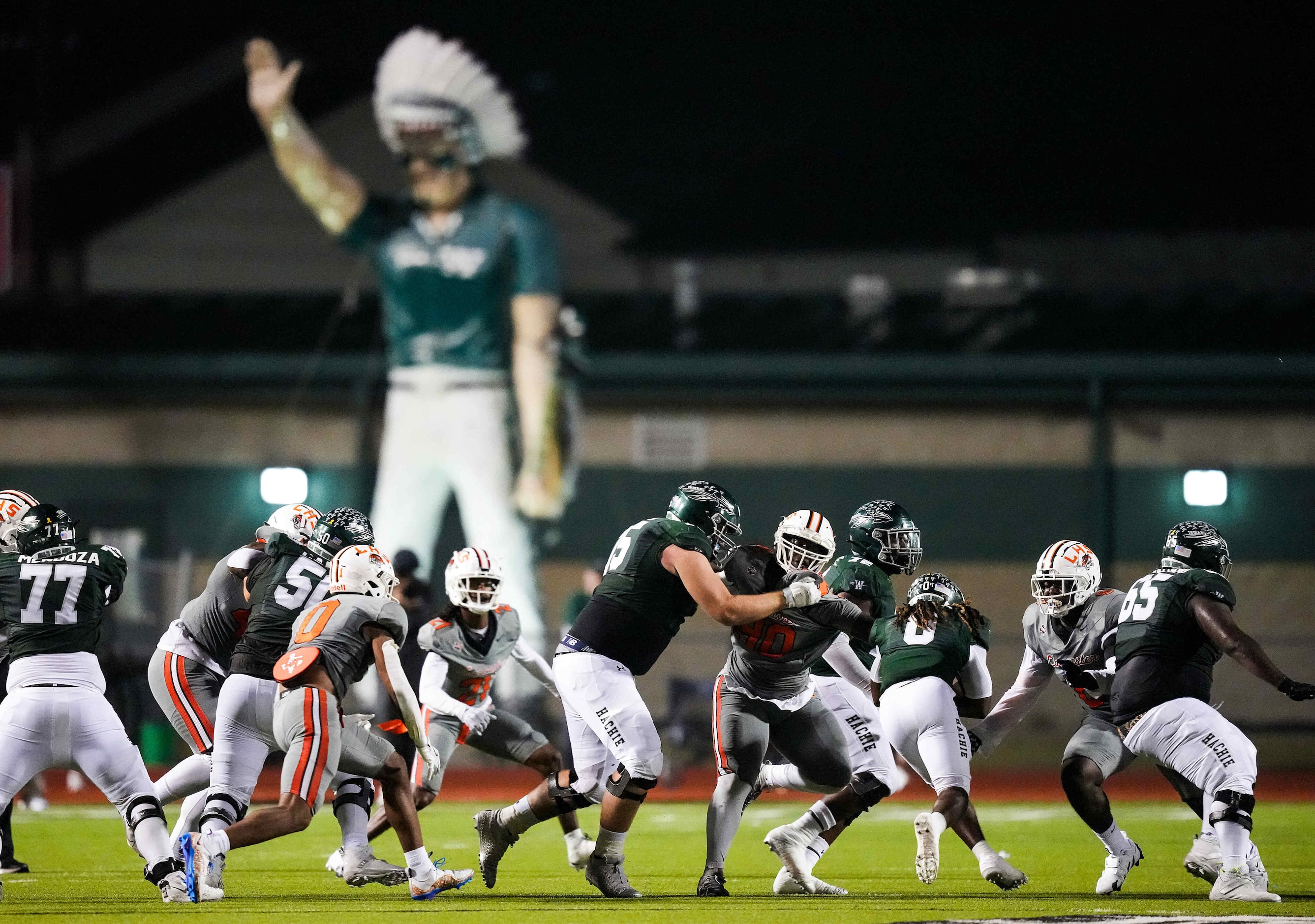 The Waxahachie Indians mascot towers over the end zone as running back  Bryson Linnear (0)...