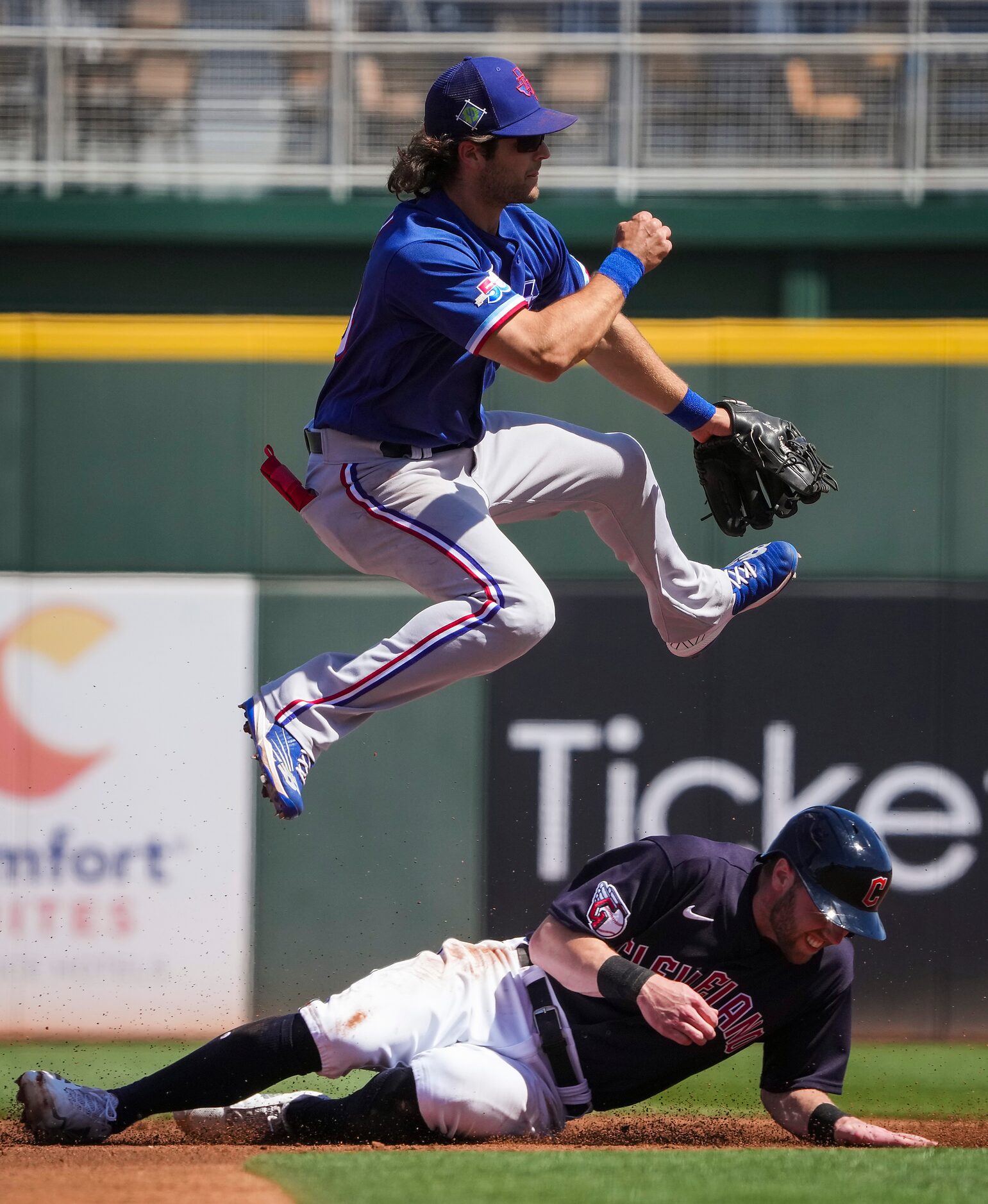 Texas Rangers shortstop Josh Smith leaps over the Cleveland Guardians Owen Miller to...