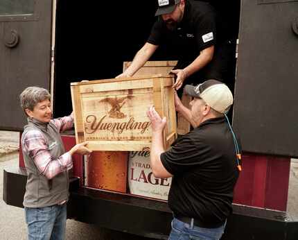 (From left) Jennifer Yuengling, Edgardo Villarroel and Jim Crawford unload crates carrying...