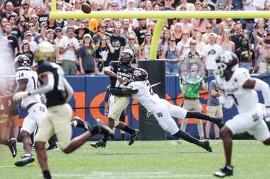 Brendon Lewis #12 of the Colorado Buffaloes makes a pass while being tackled by Micheal...
