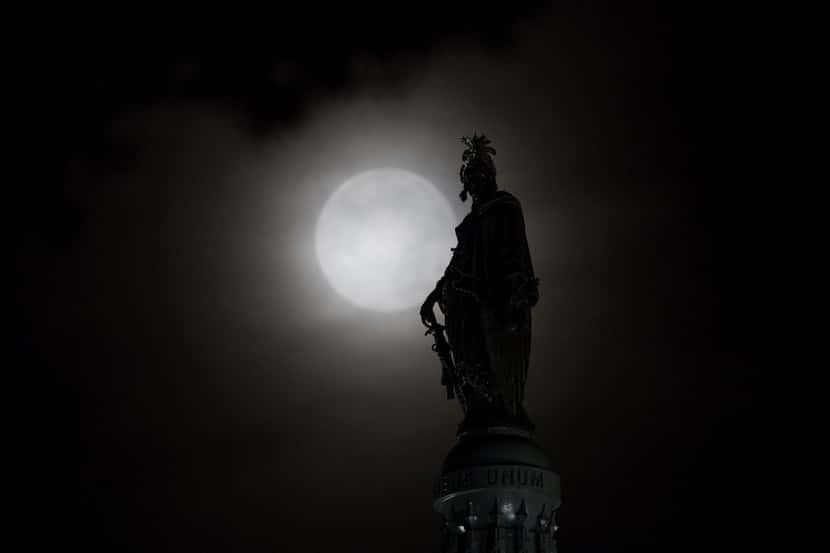 The moon is seen behind the Statue of Freedom atop the Capitol Dome in Washington, July 17,...