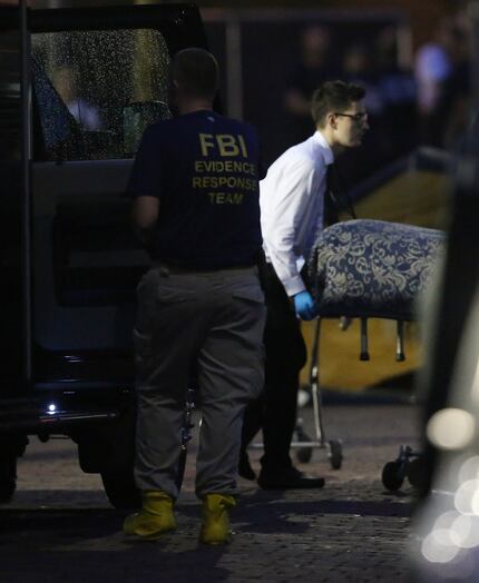  A member of the Medical Examiners office wheels a body to a vehicle from the mass shooting...