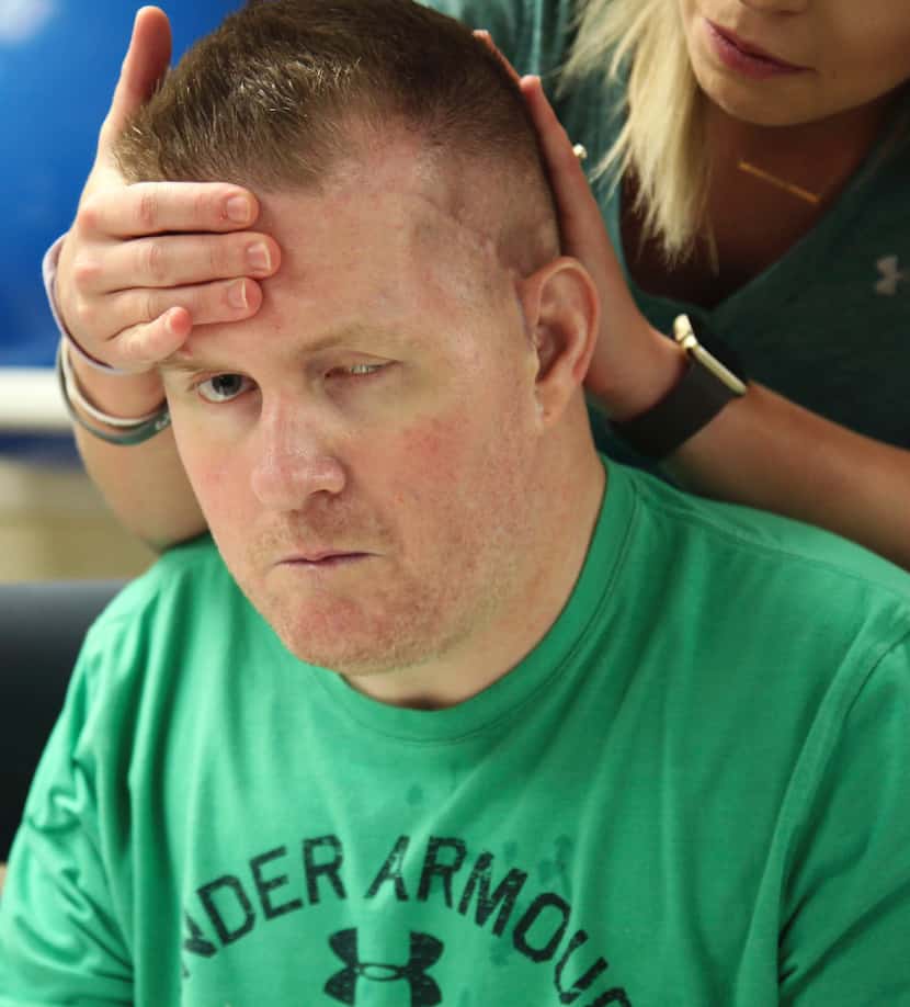 Danielle McNicoll, fiancee of Cpl. Nick Tullier, holds his head during his physical therapy...