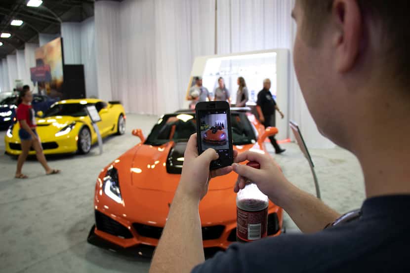 Fairgoers take in the cars on exhibit at the Texas Auto Show, one of the events at the State...