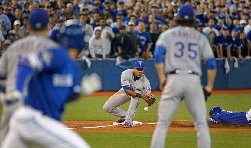 Texas Rangers shortstop Elvis Andrus (1) drops the throw from third baseman Adrian Beltre...