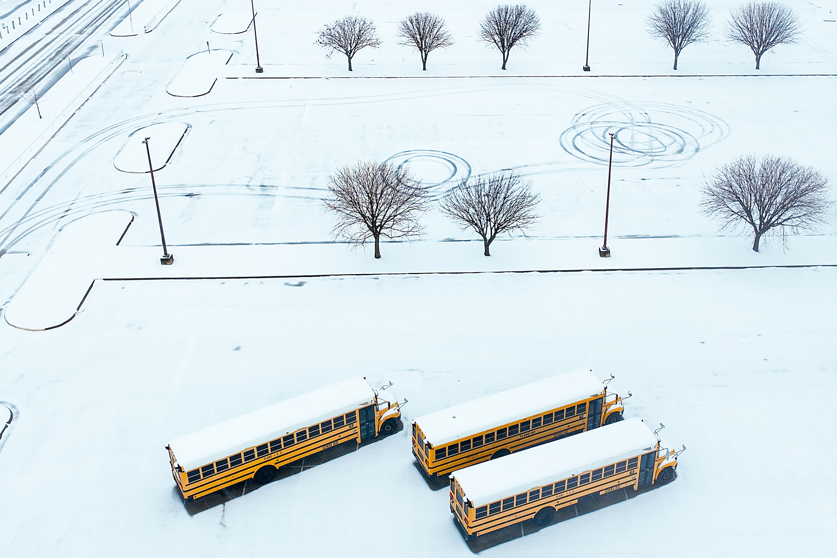 School buses sit idle in the snow at Plano Senior High School on Thursday, Jan. 9, 2025, in...