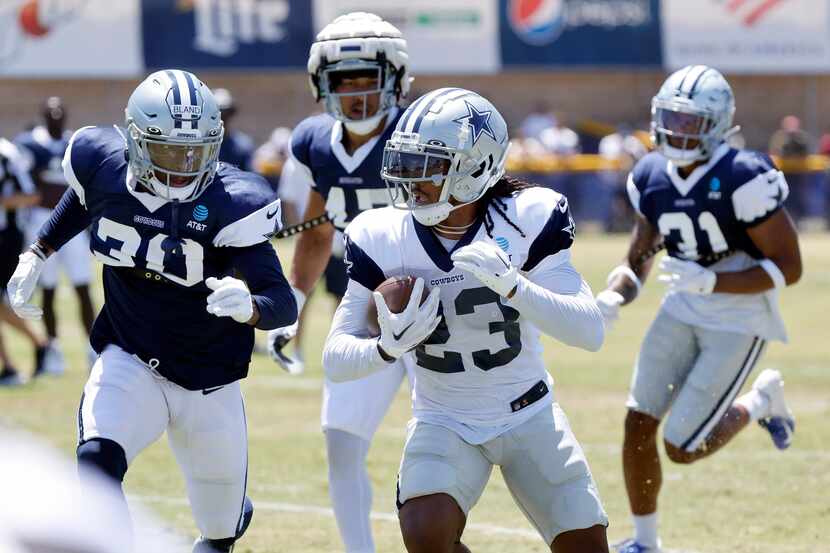 Dallas Cowboys running back Rico Dowdle (23) is pursued by cornerback DaRon Bland (30) and...