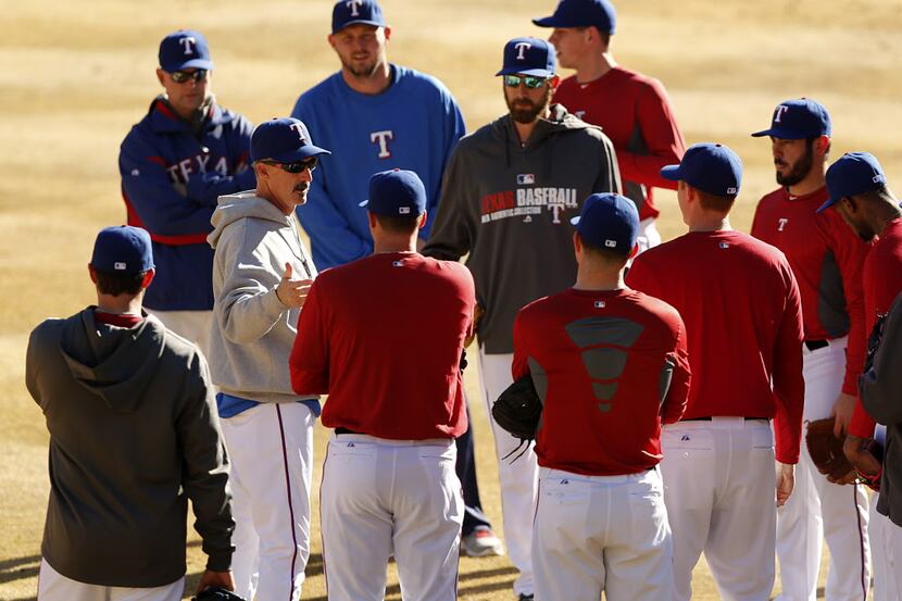 Texas Rangers pitching coach Mike Maddux (grey sweatshirt, left) huddles up his pitchers...