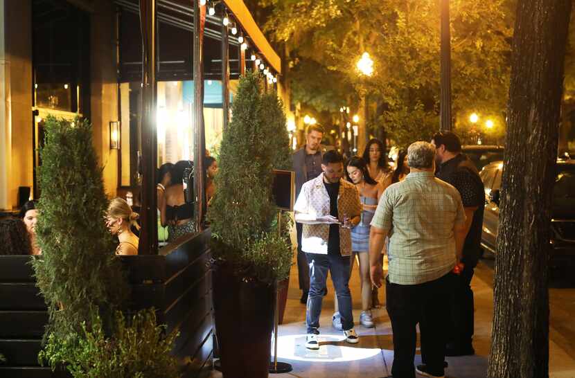 Guests wait to have their identification checked outside of Parliament Bar in Dallas.