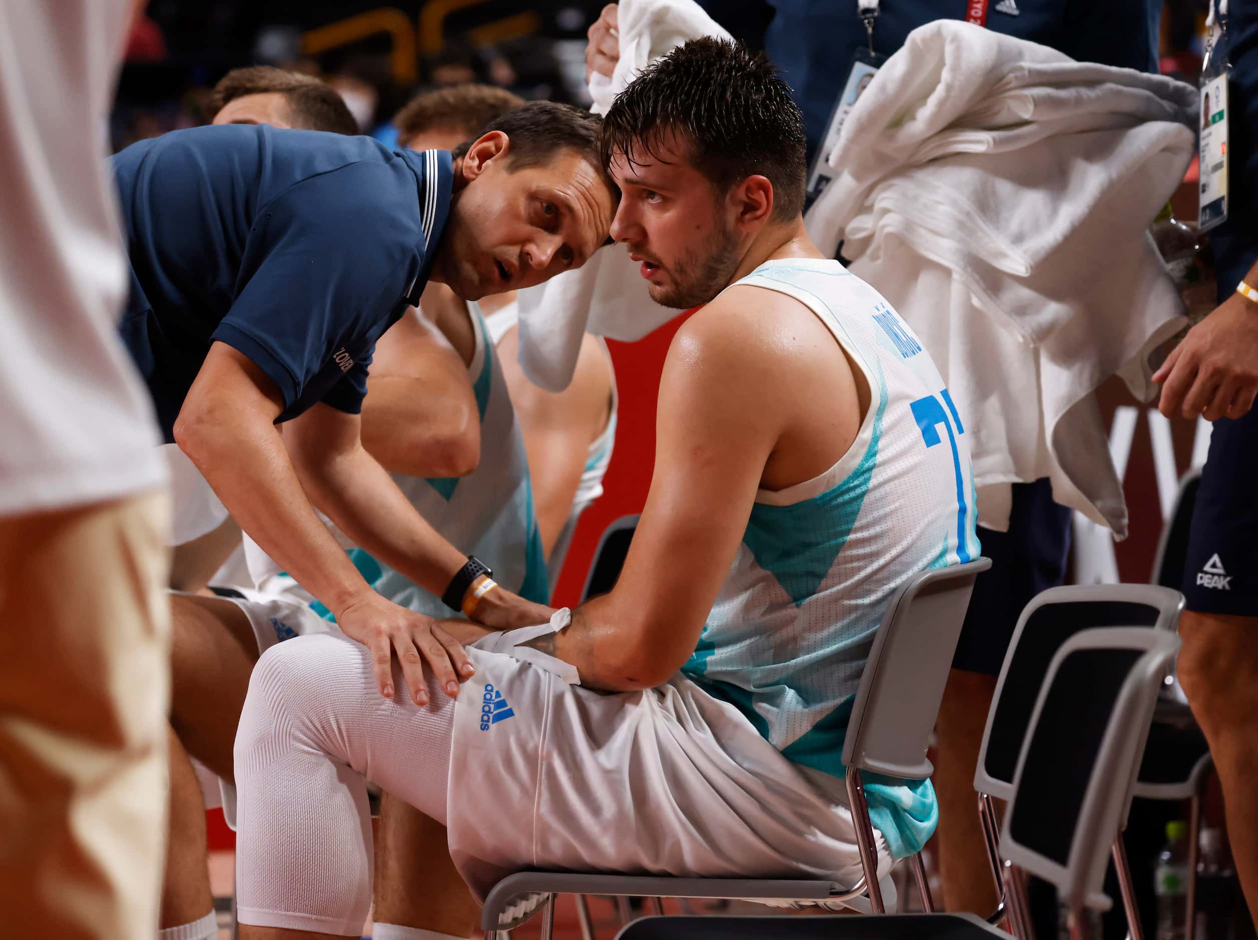 Slovenia’s head coach Aleksander Sekulic consoles Luka Doncic (77) as he sits on the bench...