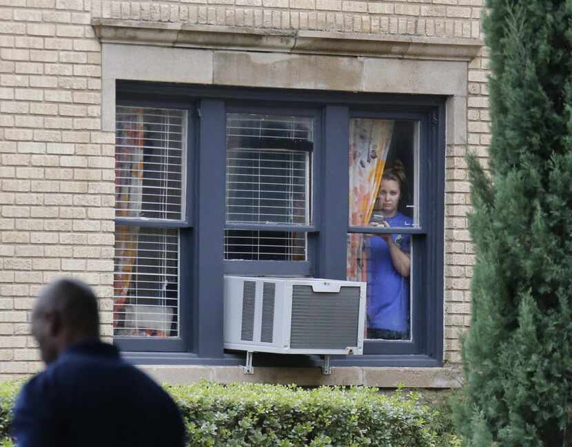 A resident peeks out the window at an apartment next door to the residence at 5700 block of ...