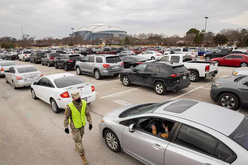 People wait in line to receive food from the Tarrant Area Food Bank in the parking lot of...