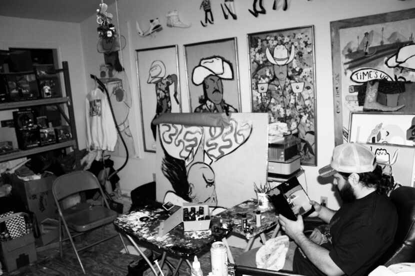 Artist Alex Lujan sits in his studio with his Bandito paintings.