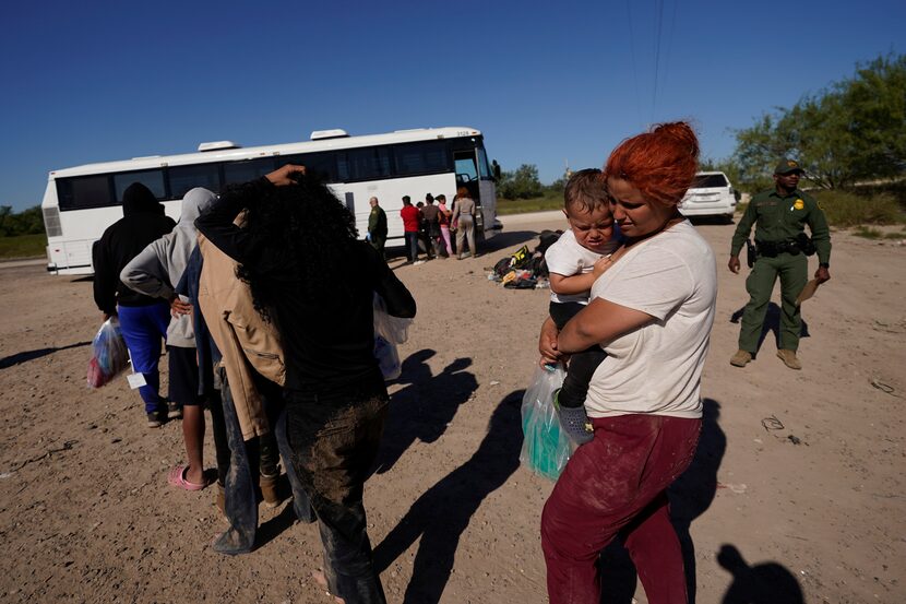 Migrants wait to board busses as they are processed by the U.S. Customs and Border Patrol...