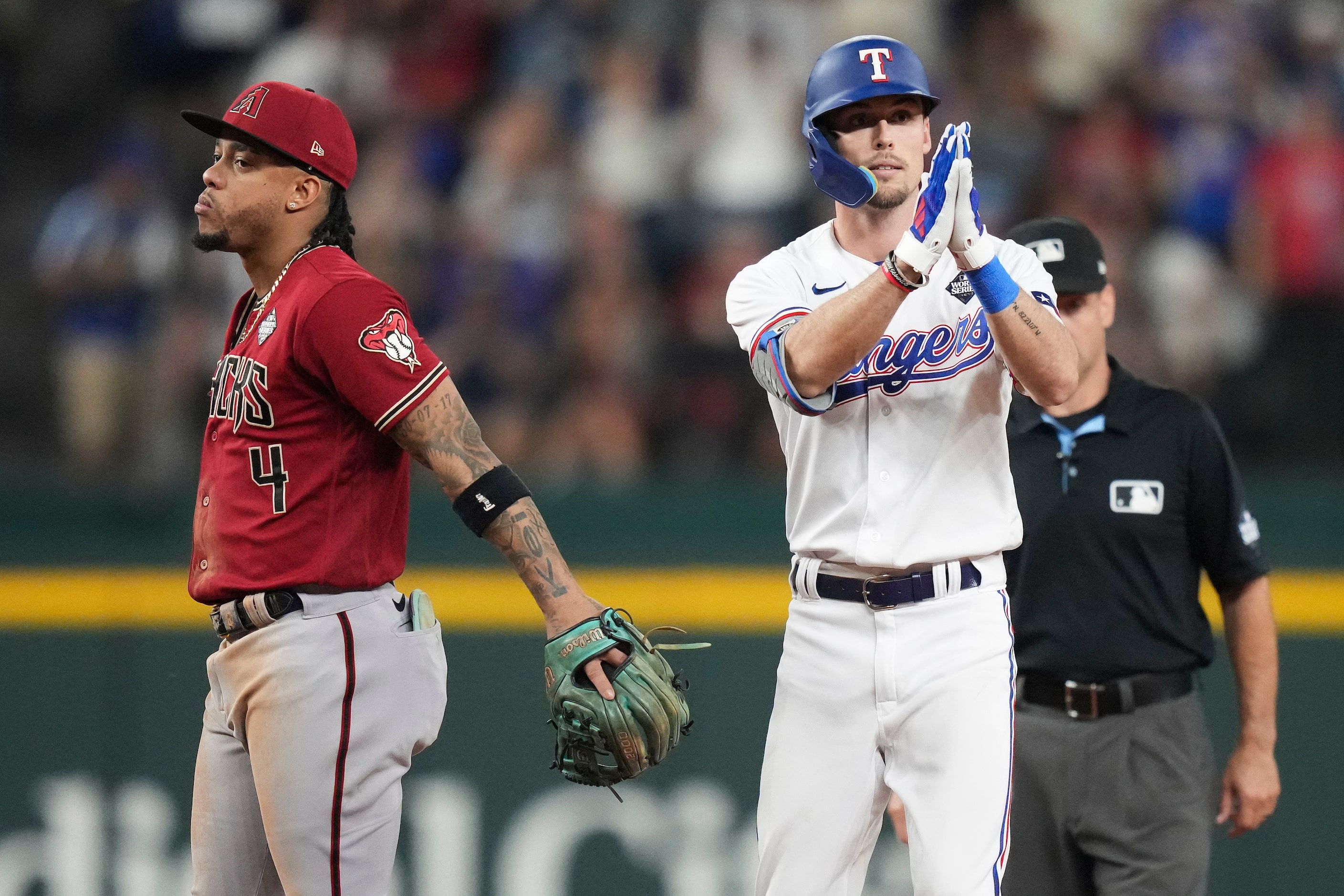 Texas Rangers' Evan Carter celebrates behind Arizona Diamondbacks second baseman Ketel Marte...