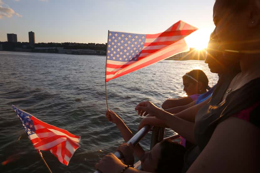 A passenger waved an American flag during a Fourth of July cruise on the Hudson River in New...