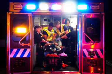Austin-Travis County EMS Commander Craig Smith (left) works in the back of an ambulance in May.