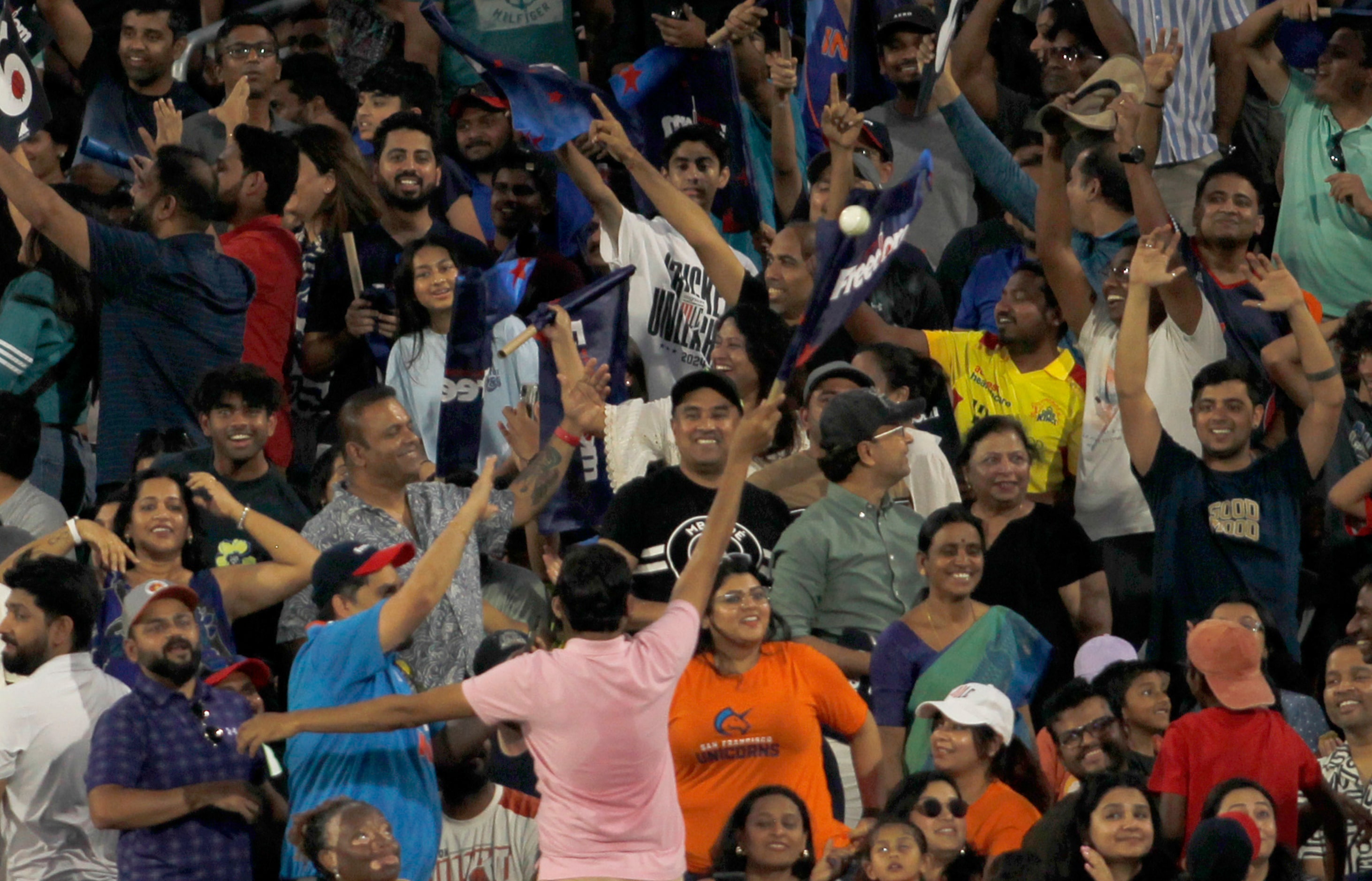 Fans return a  ball hit among the fans to the field of play during the cricket match between...