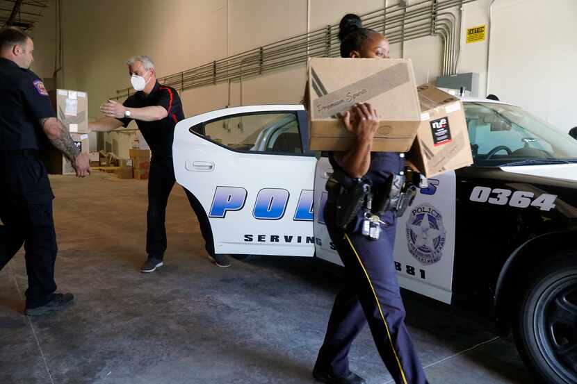 Southwest Spirits CEO Guillermo Rodriguez loads boxes of hand sanitizer into a patrol car at...