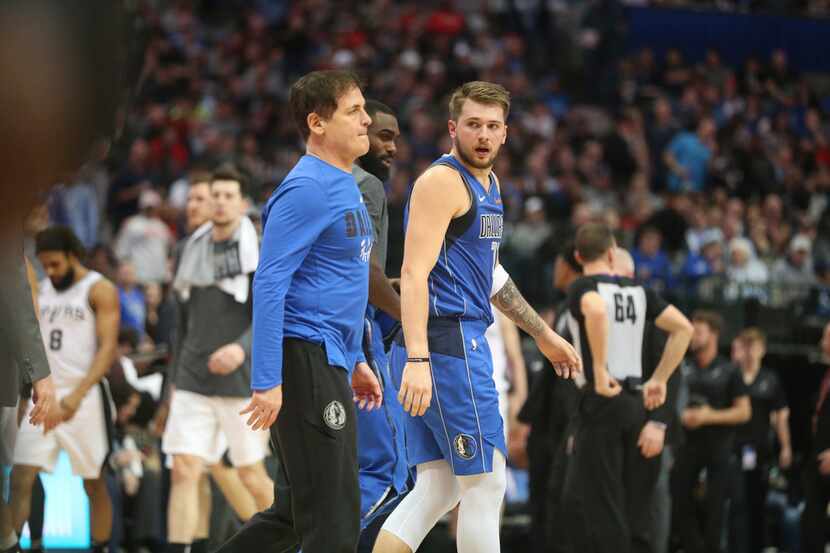 Dallas Mavericks owner Mark Cuban (left) walks to the locker room with forward Luka Doncic...