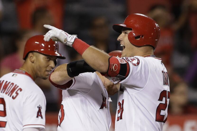 Los Angeles Angels' Mike Trout (27), right, reacts with teammates after hitting a three-run...