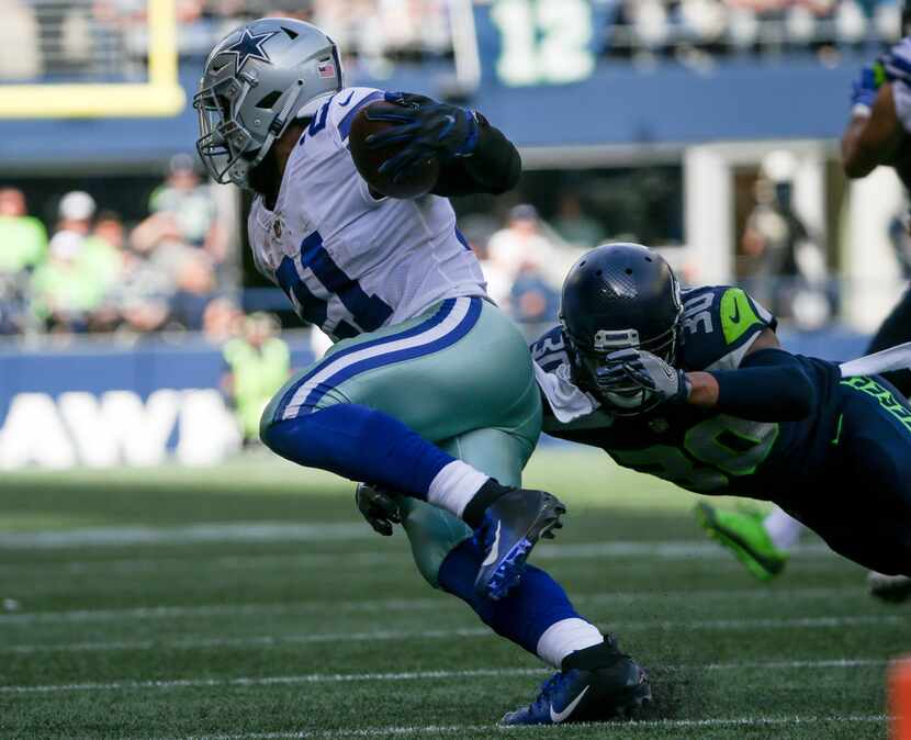 Dallas Cowboys running back Ezekiel Elliott (21) carries the ball past Seattle Seahawks...