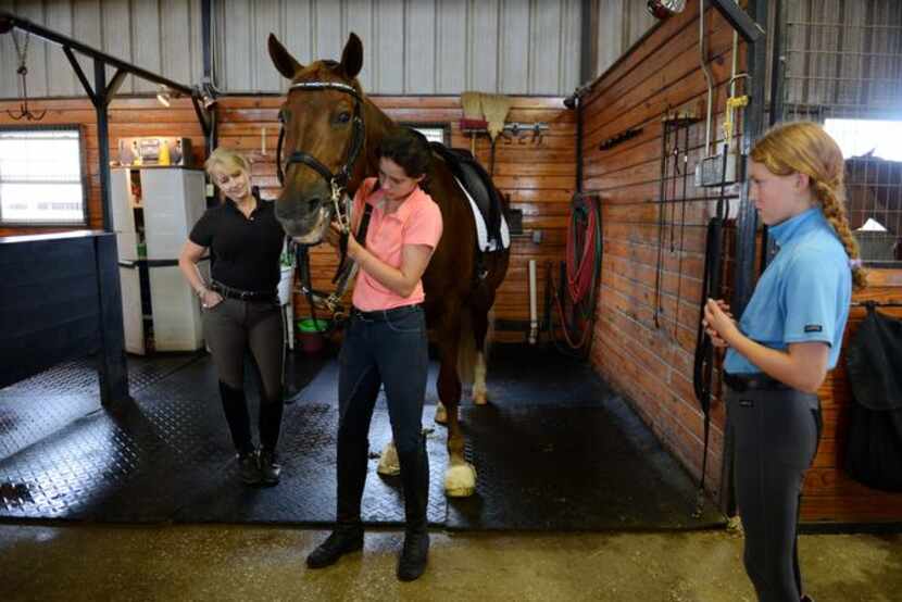 
Head trainer Lisa Blackmon (left) watches Peyton, 16, put a bridle on Irnas, while Sophie,...