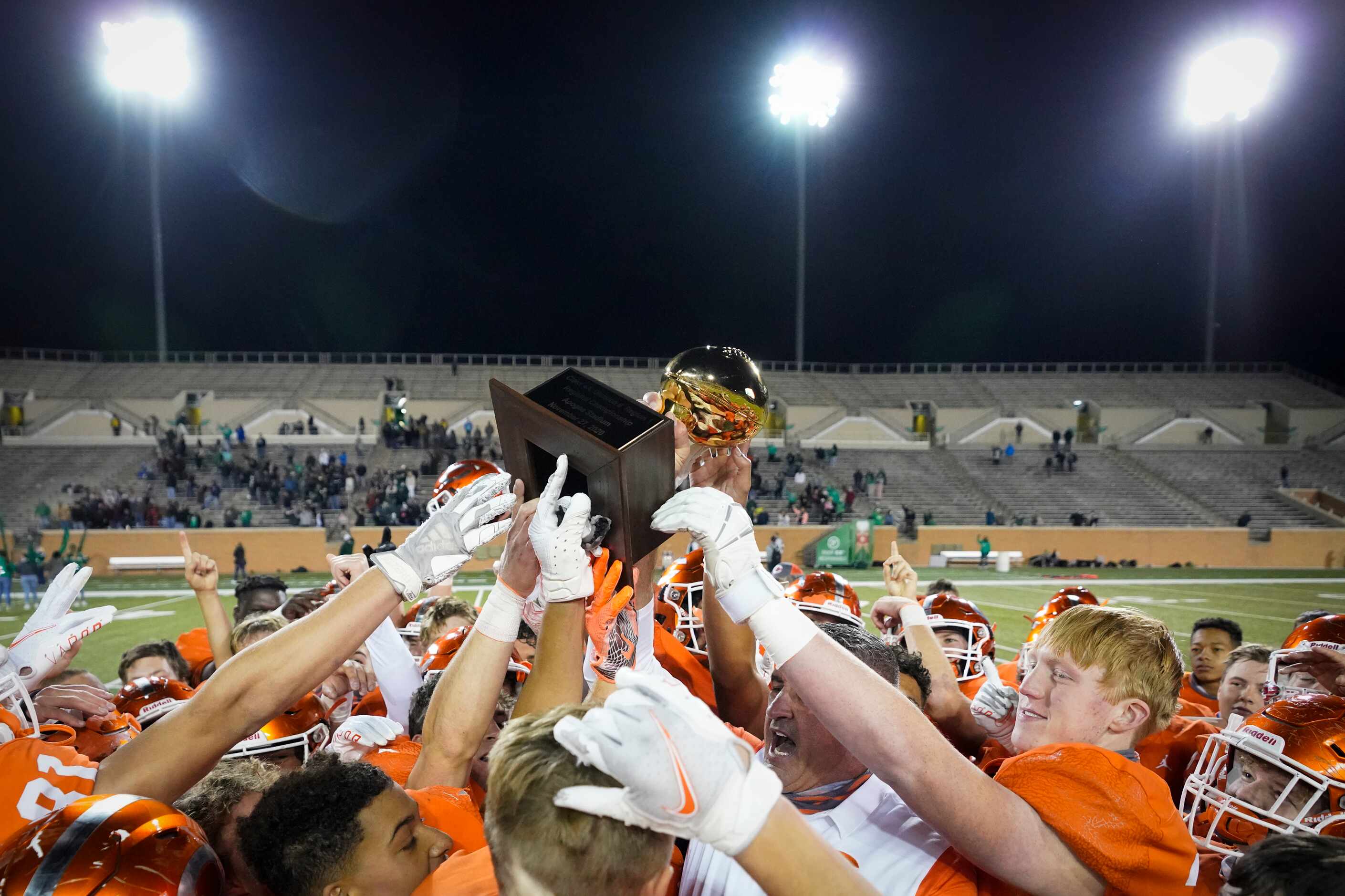 Celina players celebrate as head coach Bill Elliott  lifts the game trophy after a 42-24...
