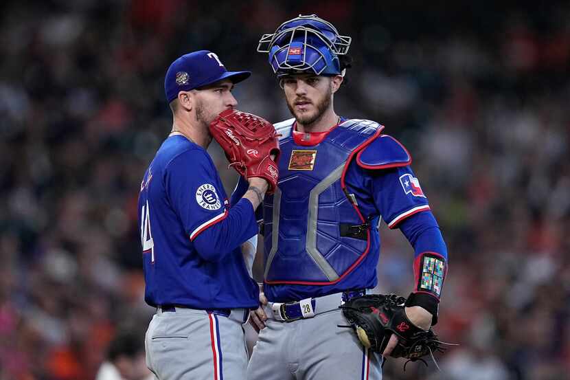 Texas Rangers starting pitcher Andrew Heaney, left, gets a visit at the mound from catcher...