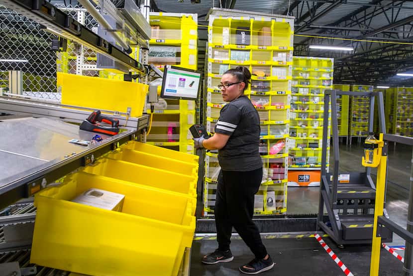 Elizabeth Moran picks up a package from a robot-delivered pod at an Amazon fulfillment...