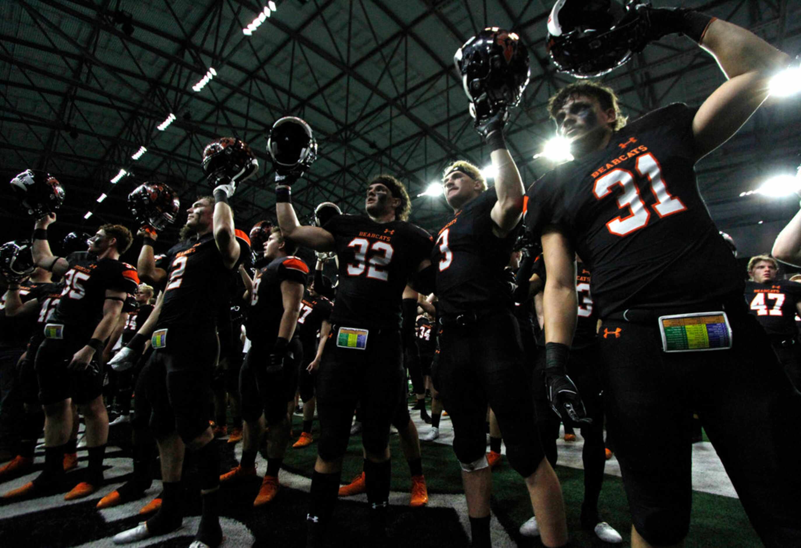 Aledo Bearcats players raise their helmets during the playing of the school song following...
