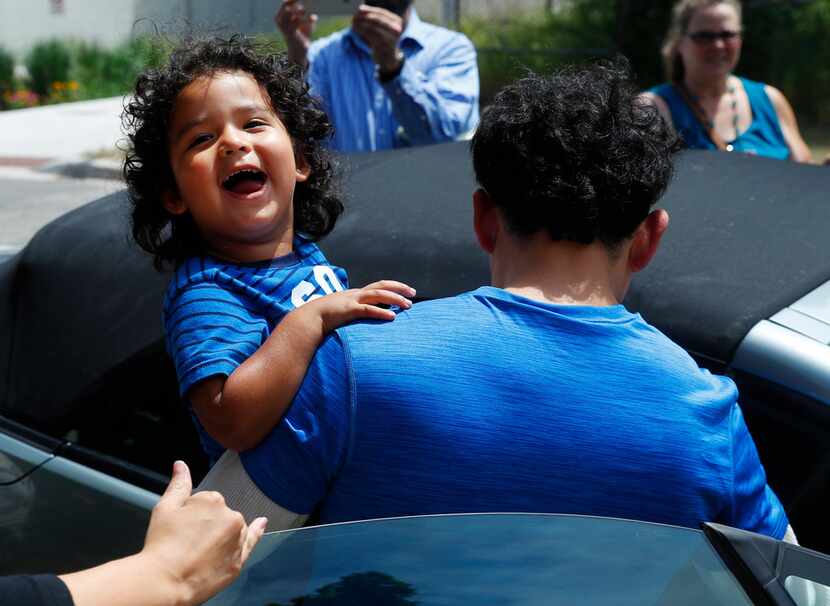 Ever Reyes Mejia, of Honduras, carries his son to a vehicle after being reunited and...