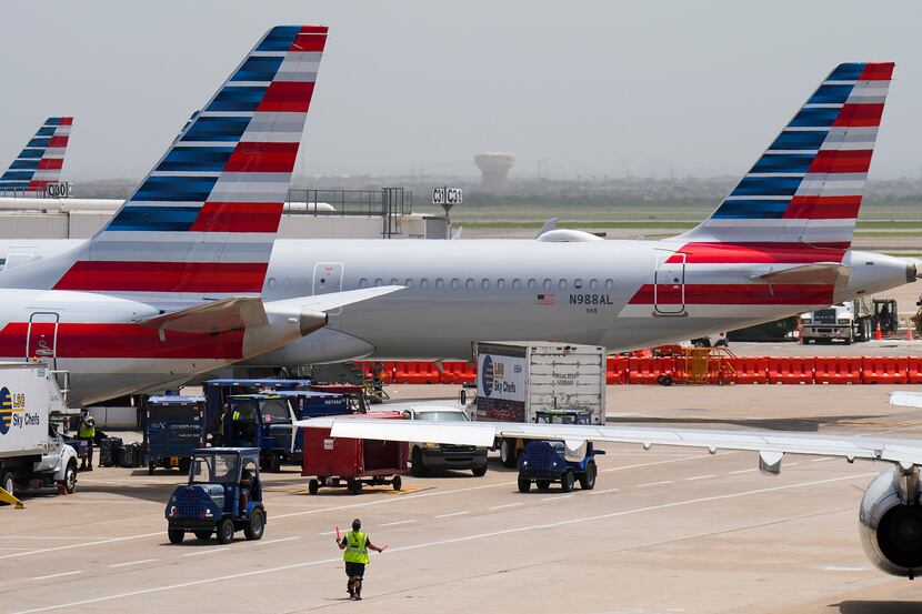 A ramp worker directs an aircraft as American Airlines planes are seen at at Terminal C at...
