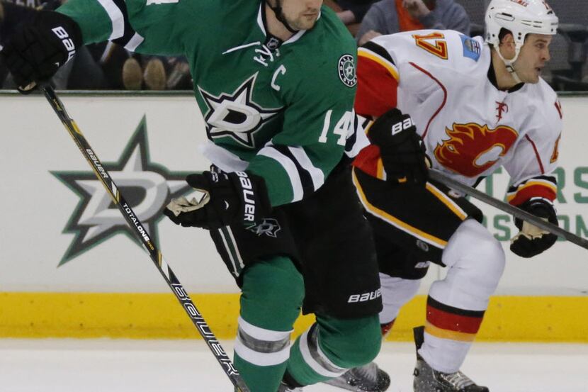 Dallas' Jamie Benn (14) brings the puck up ice past Calgary's Lance Bouma (17) in the first...