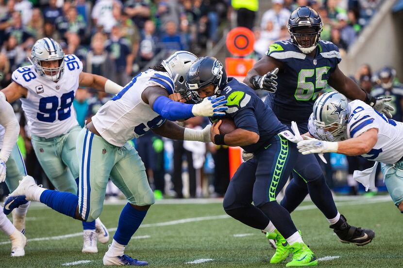 FILE - Seahawks quarterback Russell Wilson (3) is sacked by Cowboys defenders DeMarcus...
