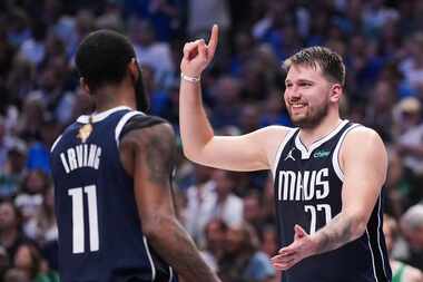 Dallas Mavericks guard Luka Doncic laughs with guard Kyrie Irving (11) after being called...